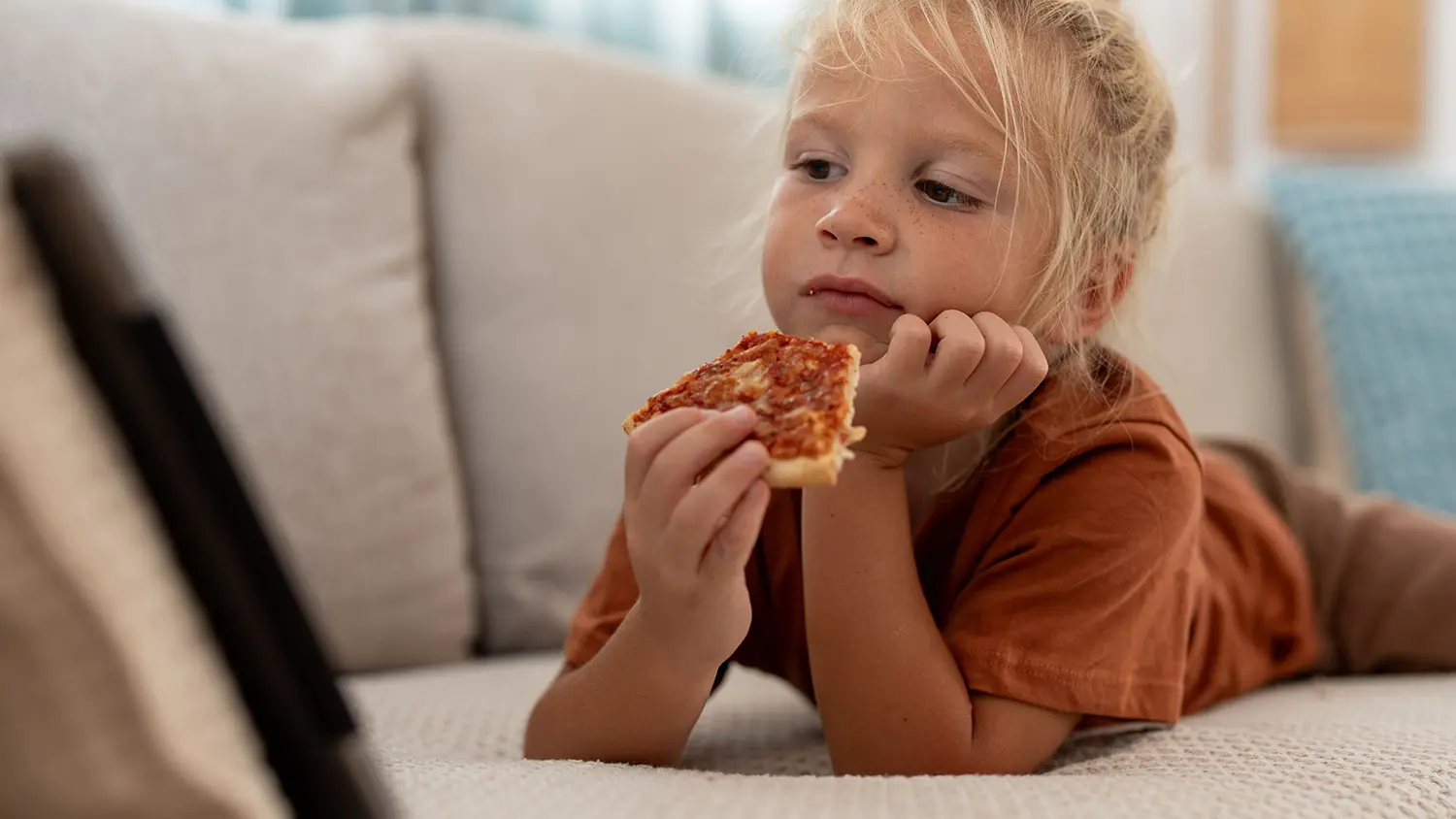 Dítě jí pizzu na sedačce
