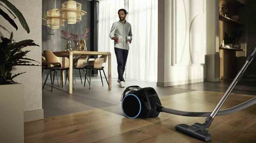 Vysavač Miele Boost CX1 Blue Pulse Obsidian čern&aacute; v interi&eacute;ru s mužem v pozad&iacute;_02