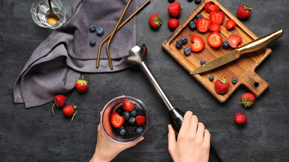 Ženské ruce připravující ovocné smoothie tyčovým mixérem_04