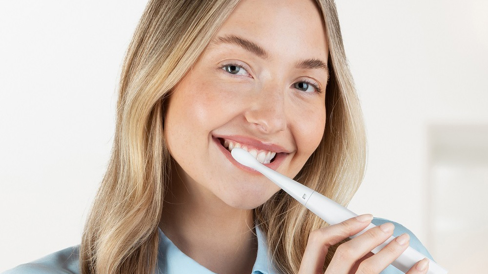 Žena si s úsměvem čistí zuby sonickým zubním kartáčkem Niceboy ION Sonic Lite_03