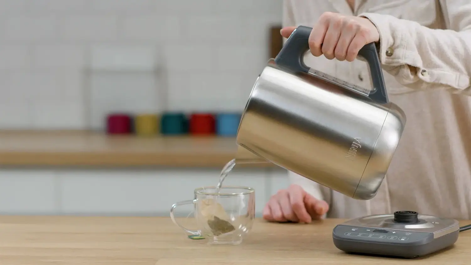 Žena nal&eacute;vaj&iacute;c&iacute; vodu z konvice Ninja KT201EU