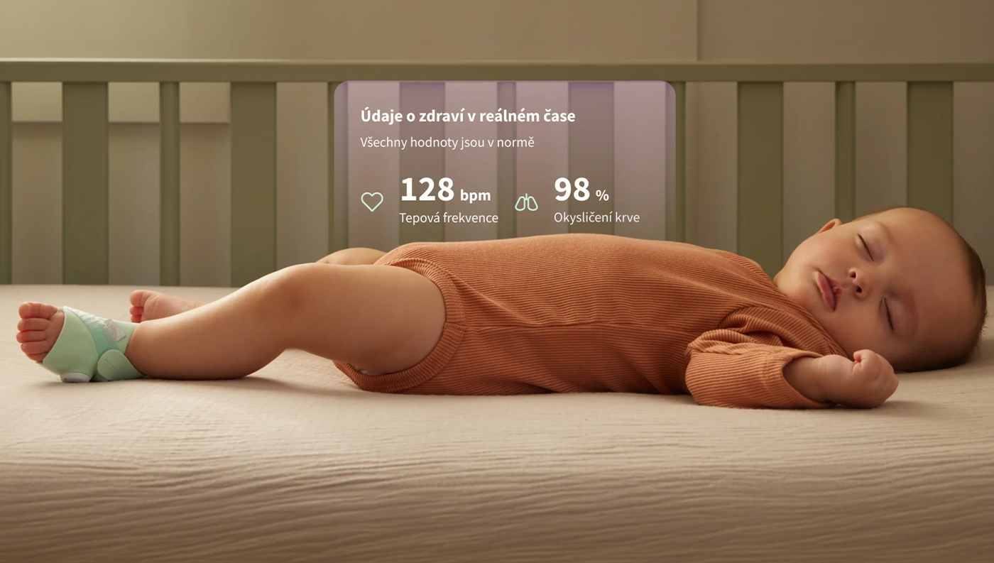Spící miminko na posteli s nasazenou chytrou ponožkou Owlet Dream Sock mintové barvy