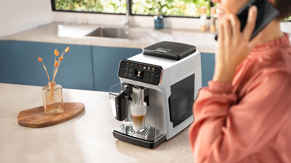 Žena telefonující vedle automatického kávovaru Philips LatteGo EP4443/70_06