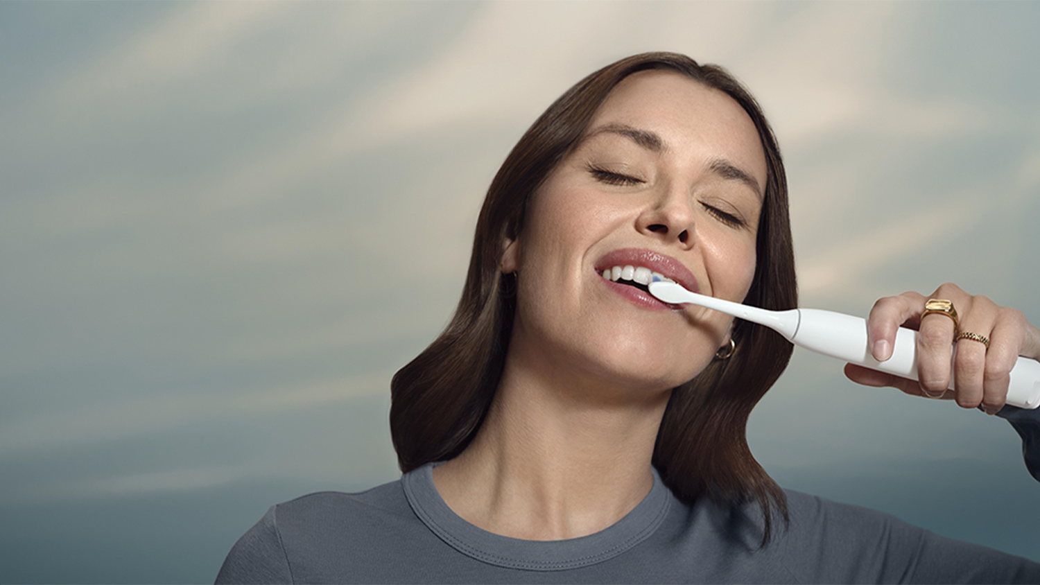 Žena si spokojne čist&iacute; zuby vďaka Optimal white hlavici a SmarTimer a BrushPacer technol&oacute;gi&aacute;m