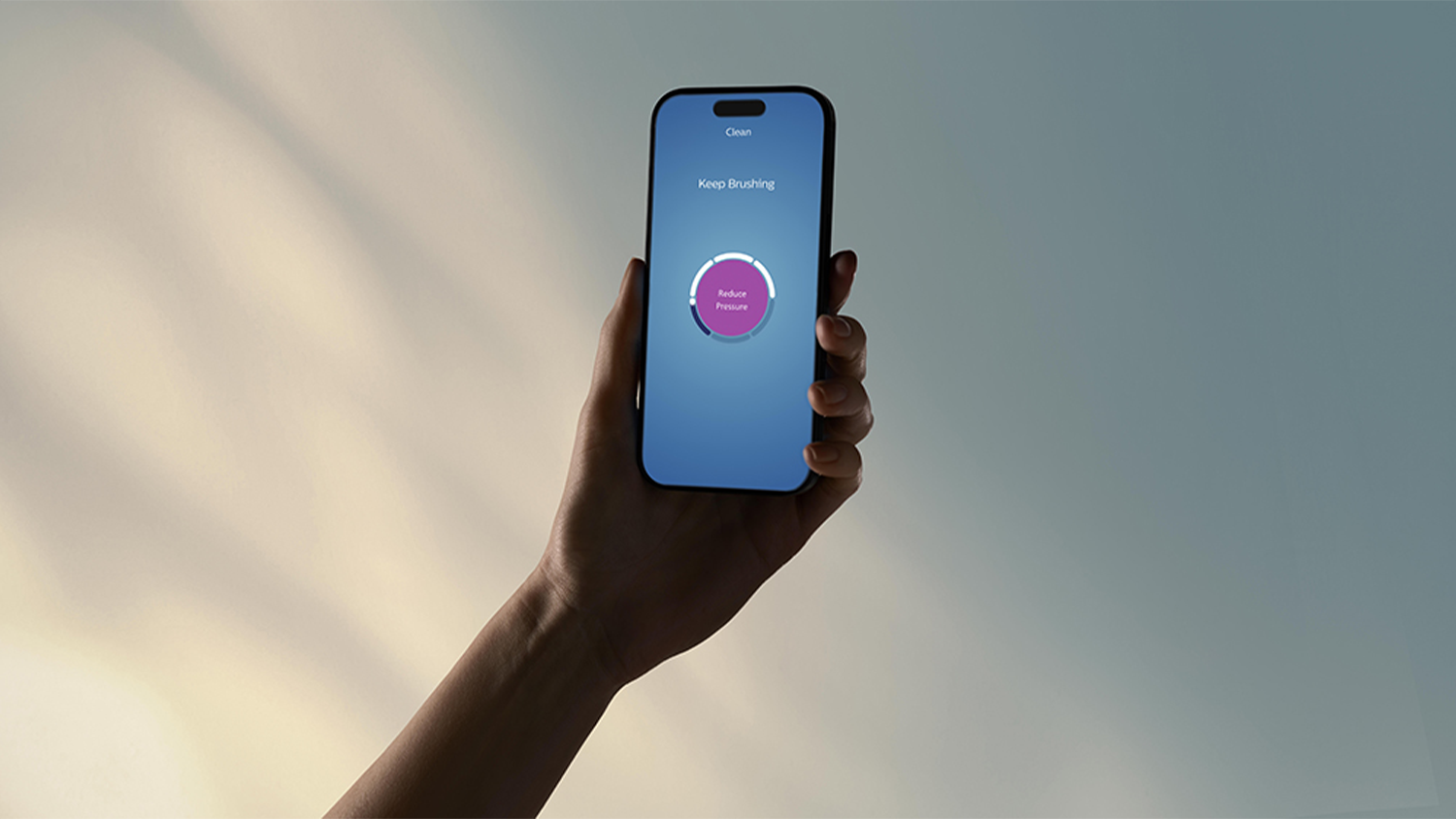 Ruka držící telefon s ukázanou mobilní aplikací pro sonický kartáček