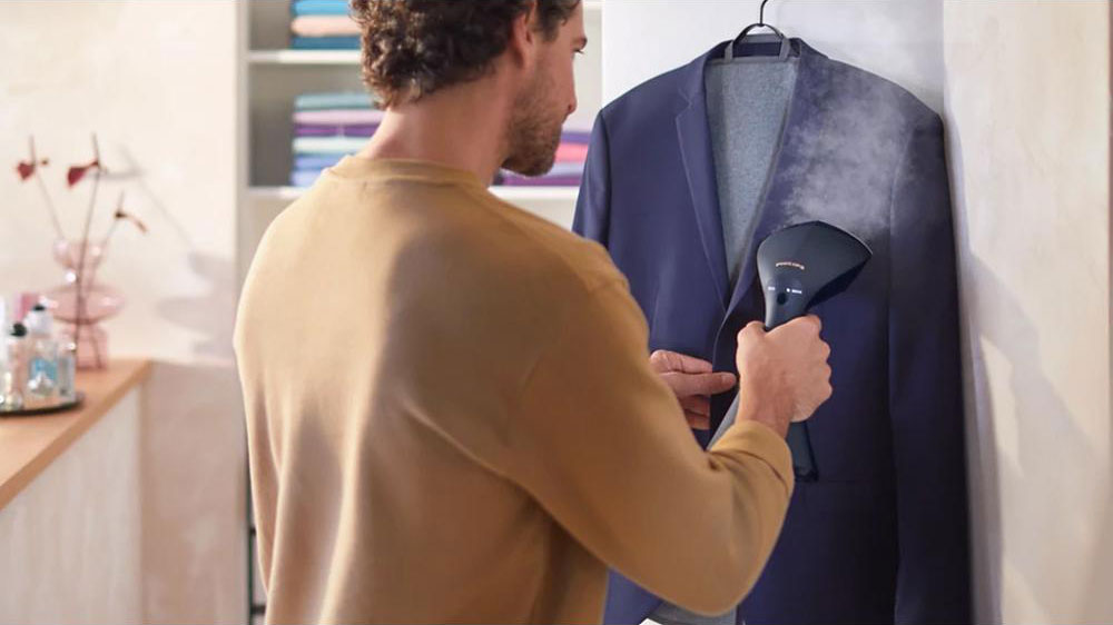 Muž napařující si oblek na ramínku ručním napařovačem Philips GC810/20_02