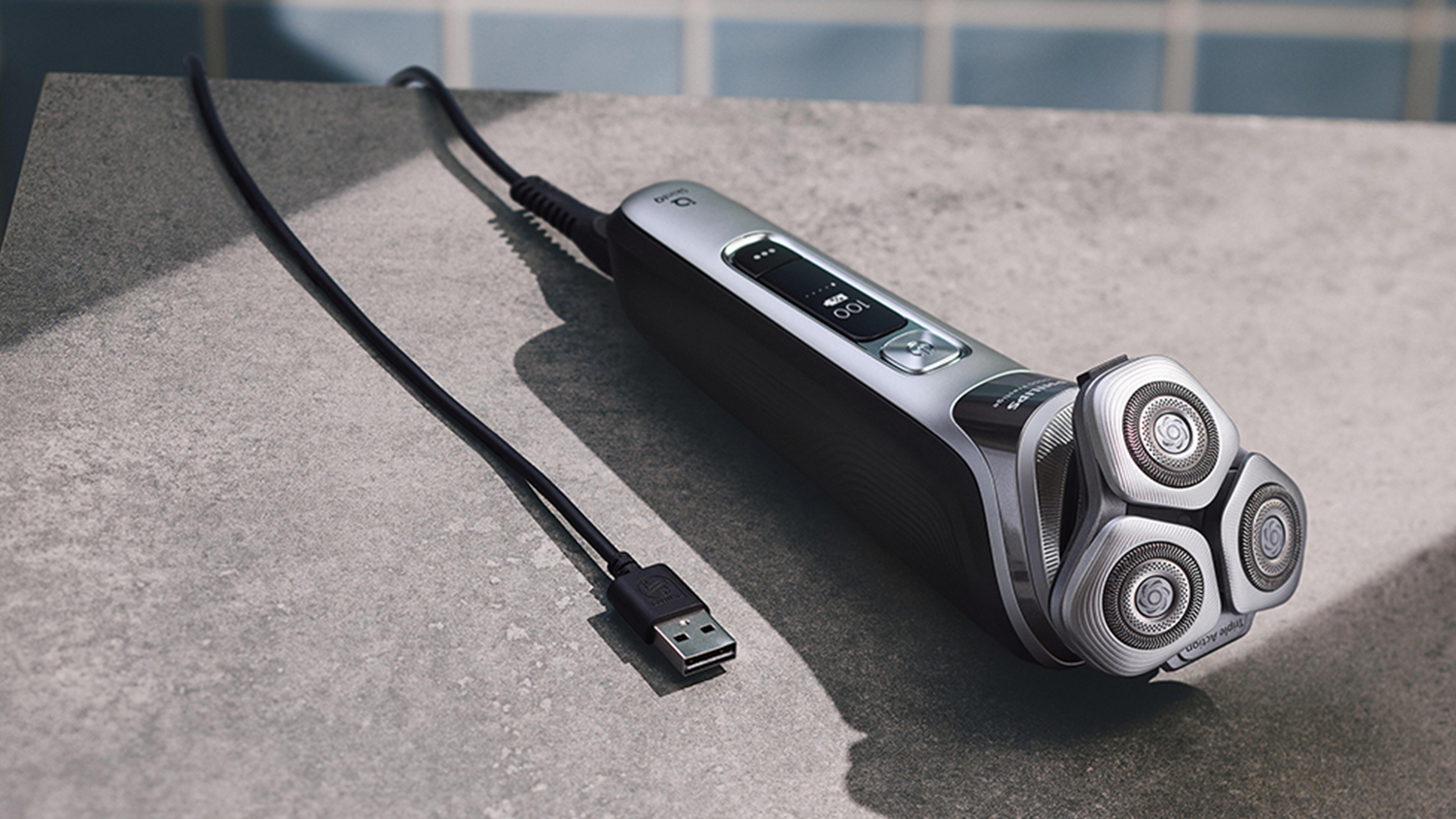 Pánský elektrický holicí strojek XP9202/10 Philips Series i9000 Prestige na stole s nabíjecím USB kabelem