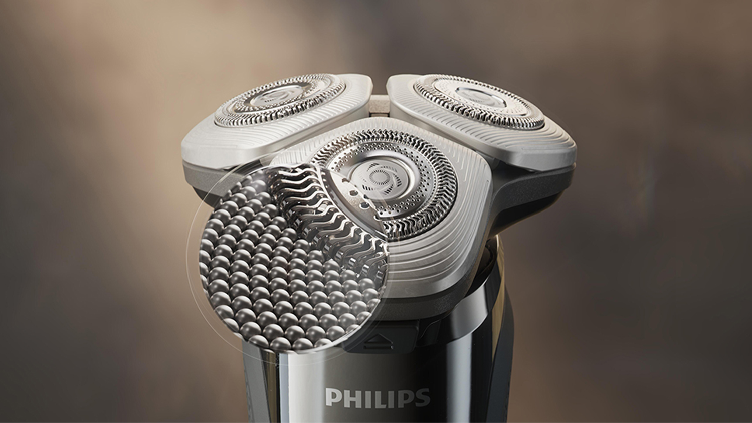 Pánský elektrický holicí strojek X9002/10 Philips Series i9000 s přiblíženým detailem na hydrofilní povrch s mikrokuličkami