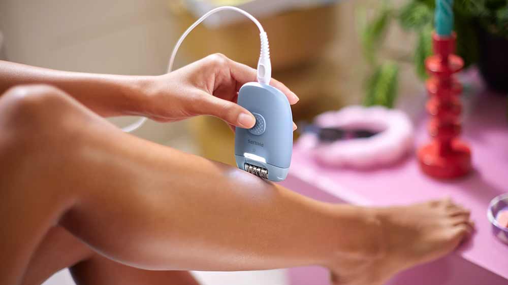 Žena si vytrh&aacute;v&aacute; chloupky na nohou pomoc&iacute; epil&aacute;toru Philips 4000 BRE247/00 s LED světlem_02