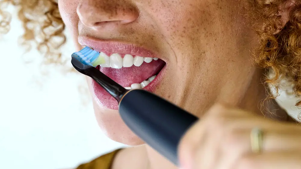 Žena si čistí zuby kartáčkem Philips s hlavicí Philips Sonicare Premium Plaque Defence HX9042/88_02