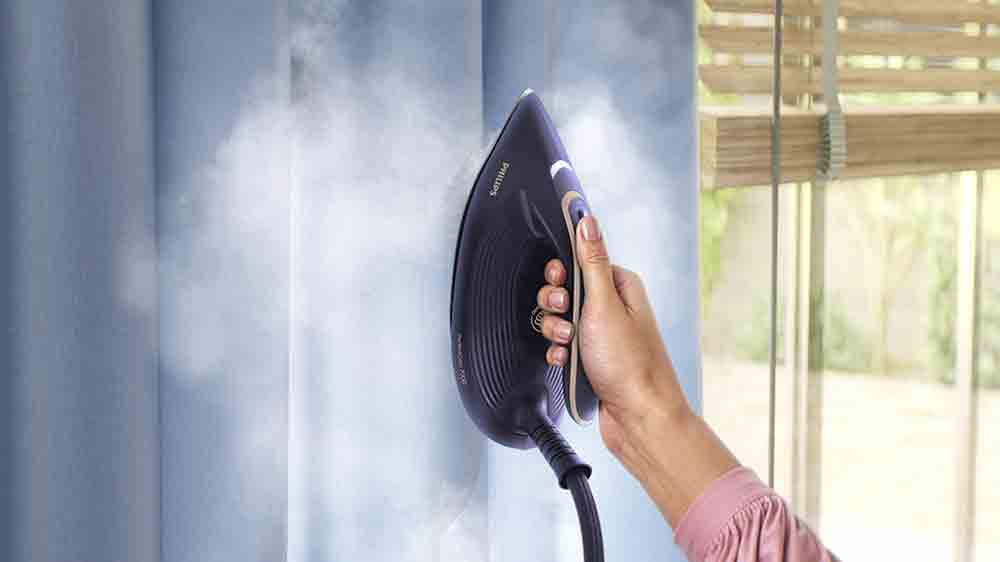 Žena s žehličkou Philips 7300 Series PerfectCare PSG7300/20 napařuje visící závěs_07