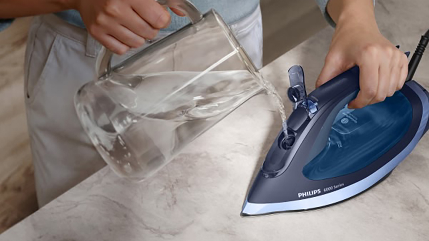 Osoba nalévá vodu do nádržky napařovací žehličky DST6120/20 Philips 6000 Series