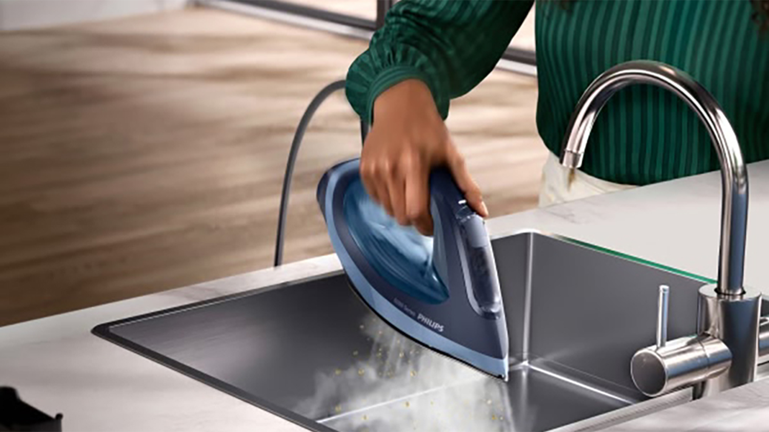 Osoba používá funkci Calc-Clean pro odstranění vodního kamene v napařovací žehličce Philips 6000 Series