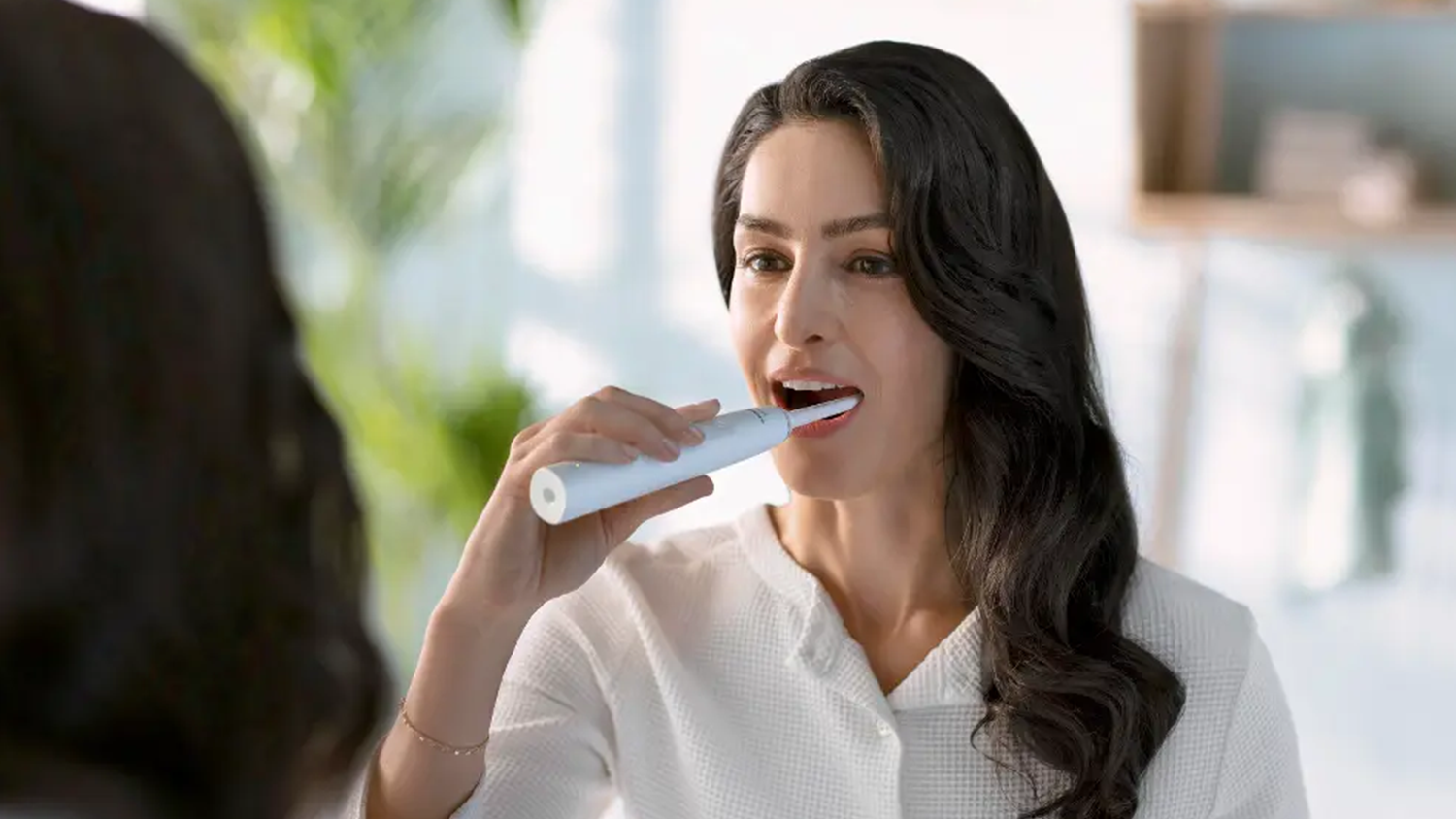 Žena si čistí zuby sonickým zubním kartáčkem Philips Sonicare 2100 HX3651/13