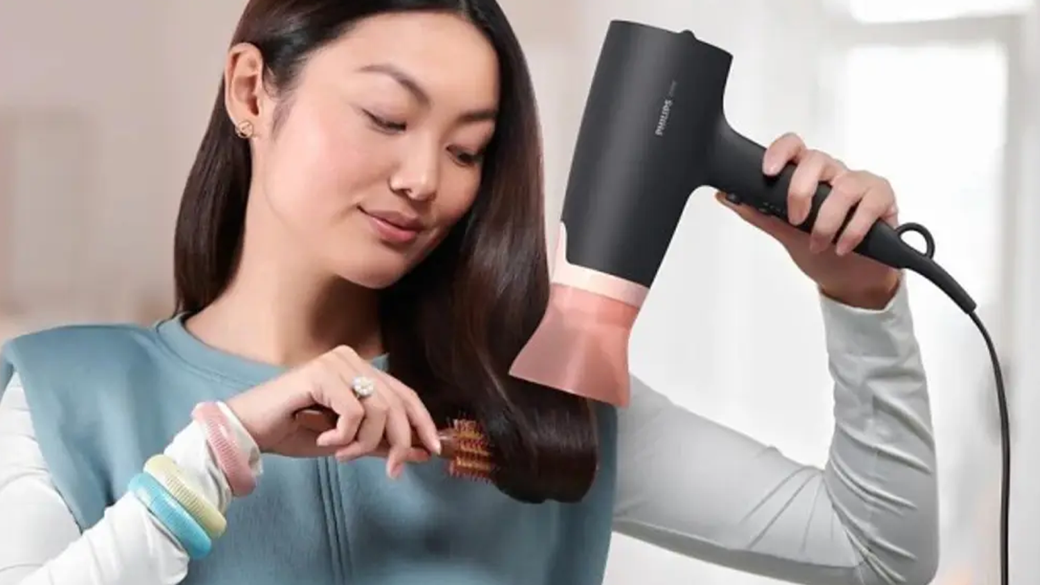 Žena upravuje účes fénem Philips BHD350/10