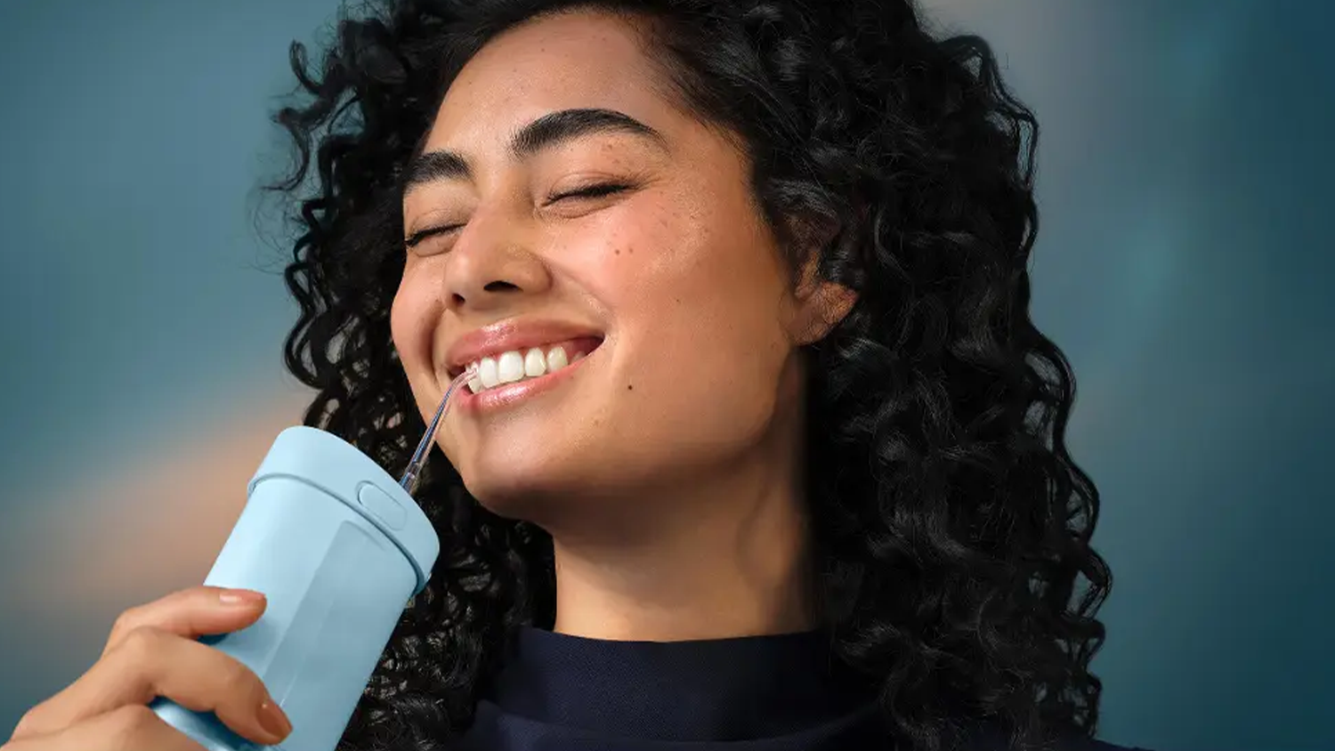 Žena si čistí zuby s ústní sprchou s hlavicí Philips Sonicare HX3072/00