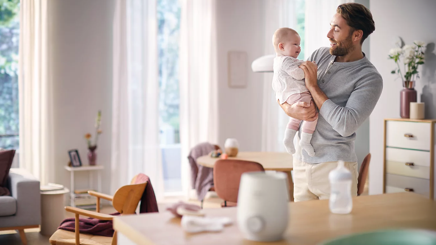 Tat&iacute;nek drž&iacute; miminko a m&aacute; před sebou ohř&iacute;vač Philips Avent Premium SCF358/00