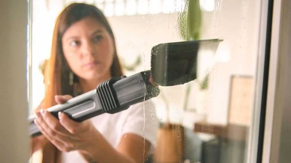 Mladá žena čistí okna pomocí parního vysavače_03