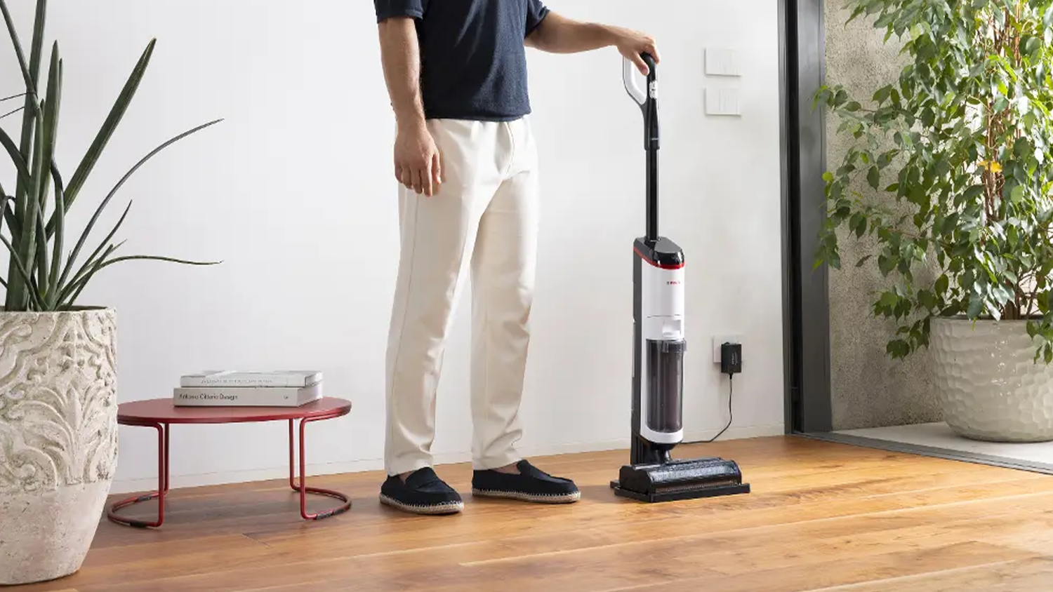 Muž stojící vedle vysavače a parního mopu Polti RollySteam WD30C