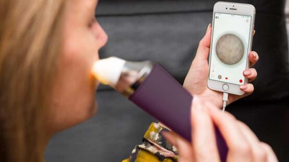 Žena používající mikrodermabraze Rio DRMC, zatímco se dívá na telefonu na průběh léčby_02