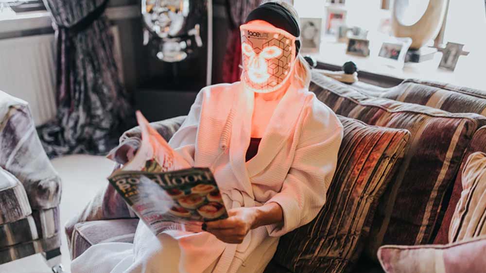 Žena používající LED masku RIO Facelite Evolution si při ošetření čte časopis_02