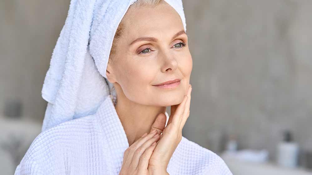 Žena ve středních letech se dotýká své mladistvě vypadající pleti_03