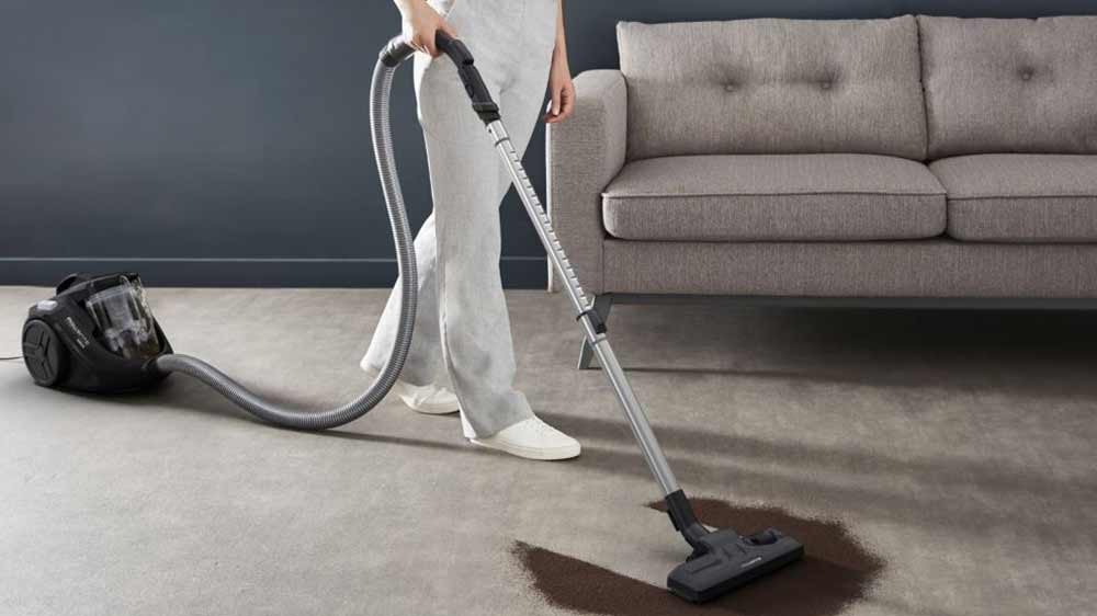 Žena vysáva koberec pred pohovkou s vysávačom Rowenta RO3725EA_05
