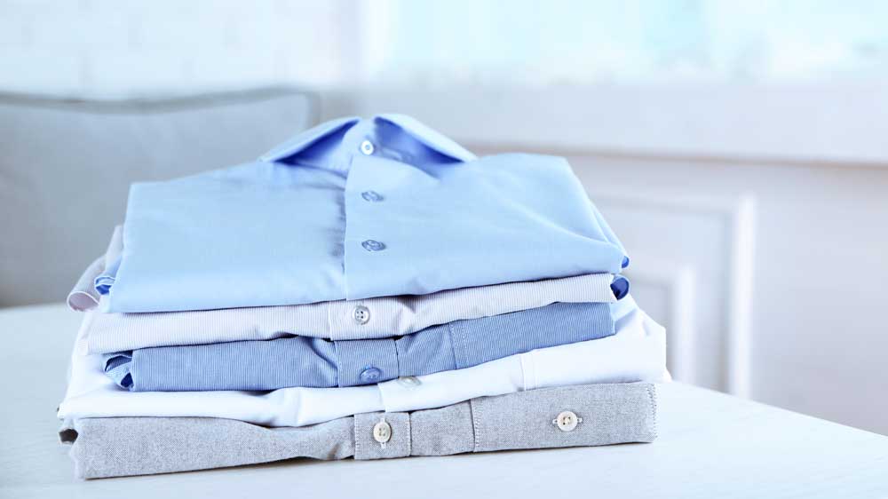 Vyžehlené a složené košile na stole_03