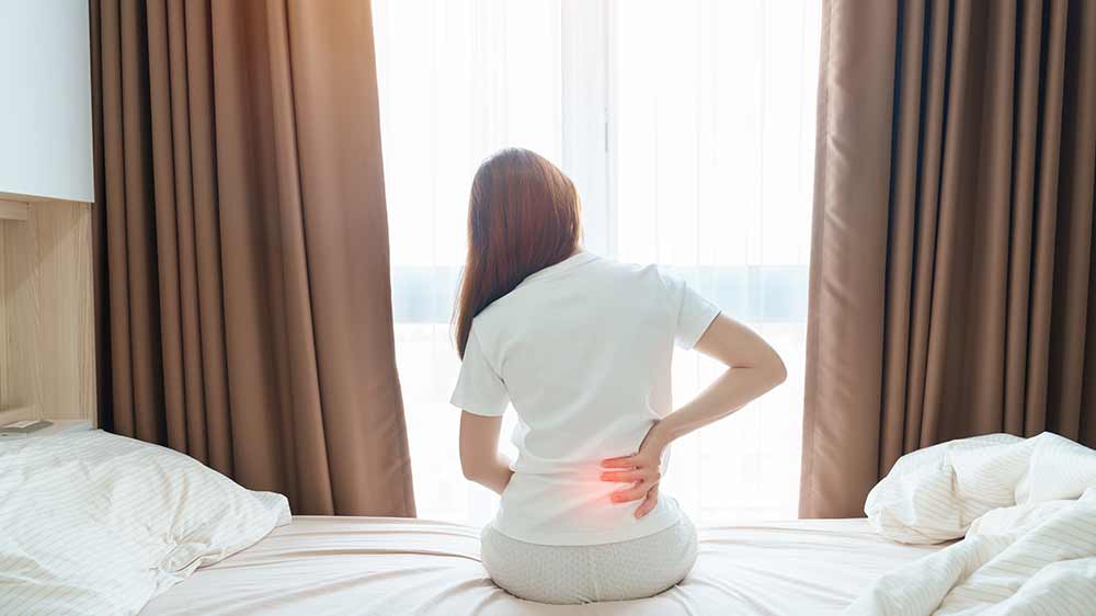 Žena s bolestí zad sedící na posteli_02