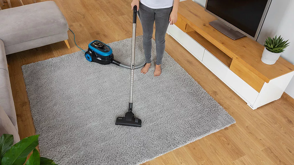 Žena vys&aacute;v&aacute; koberec bezs&aacute;čkov&yacute;m vysavačem SVC 1035TQ 3AAA_03