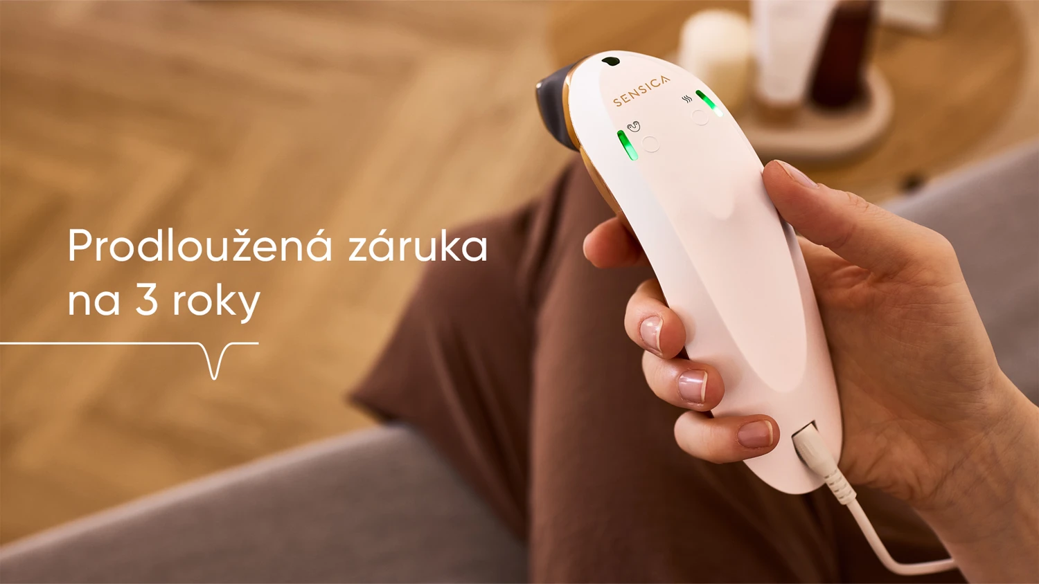 RF přístroj Sensica Sensilift™ v ruce slečny sedící na pohovce