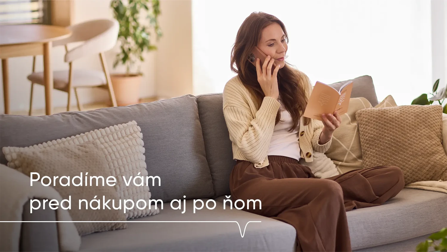 Žena sedí na gauči v obýváku, v ruce drží manuál a telefonuje