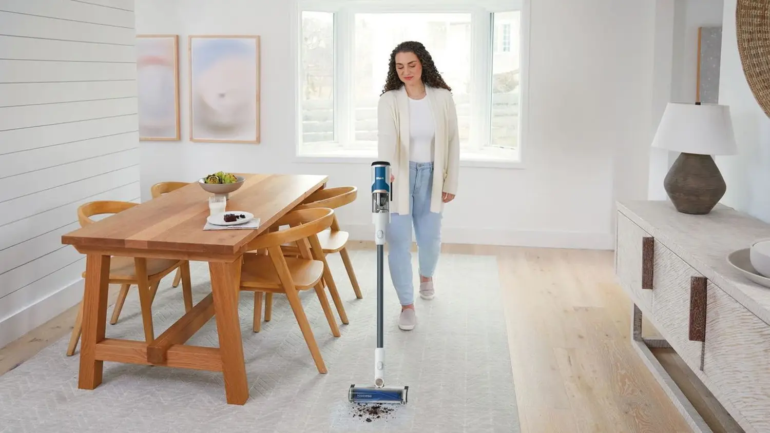 Žena při úklidu koberce pomocí tyčového vysavače Shark BU1120EU Cordless Pro