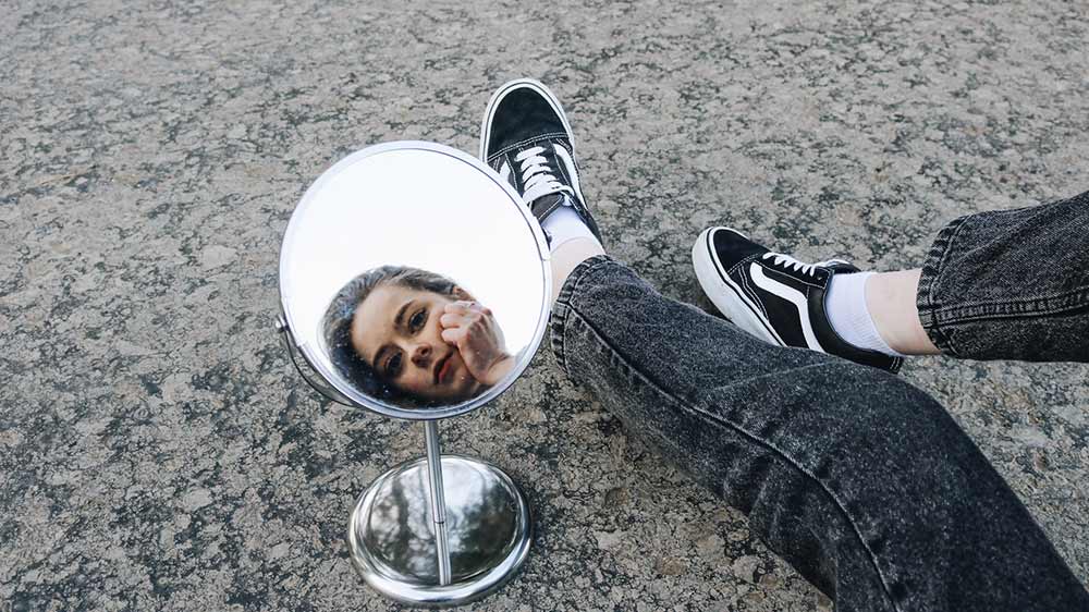 Mladá žena kouká do zrcátka položeném na zemi_03