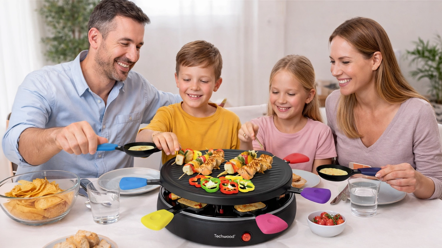Rodina griluje u stolu na raclette grilu Techwood TRA602