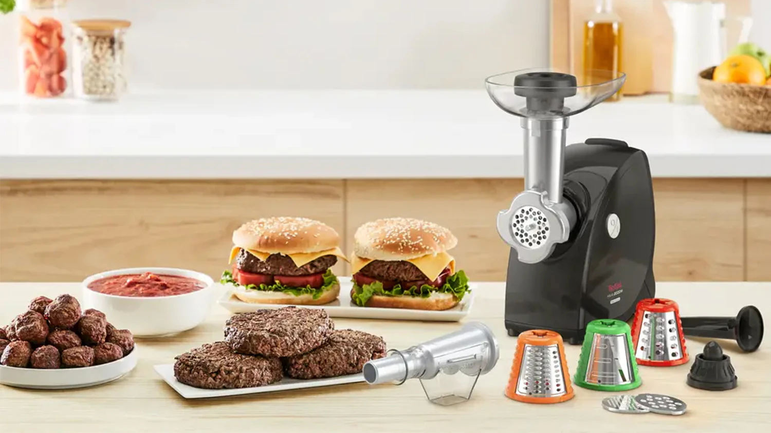 Masomlýnek Tefal HV4 Successor 9v1 NE477838 s nástavci na kuchyňské lince vedle burgerů, vytvořených masových kuliček a omáčky