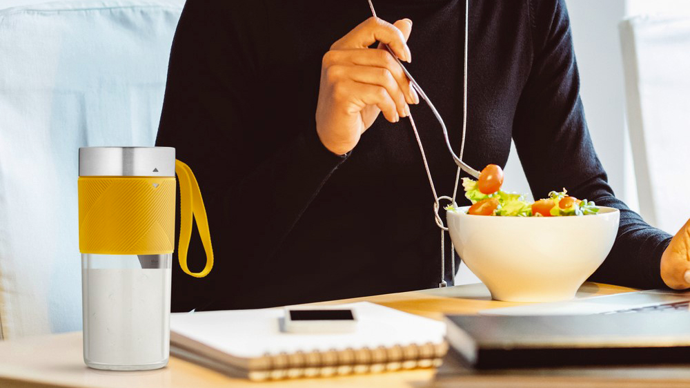 Žena, kter&aacute; j&iacute; u stolu, na kter&eacute;m je položen&yacute; smoothie mix&eacute;r Tefal Smoothie Lightmix BL1C0230_03