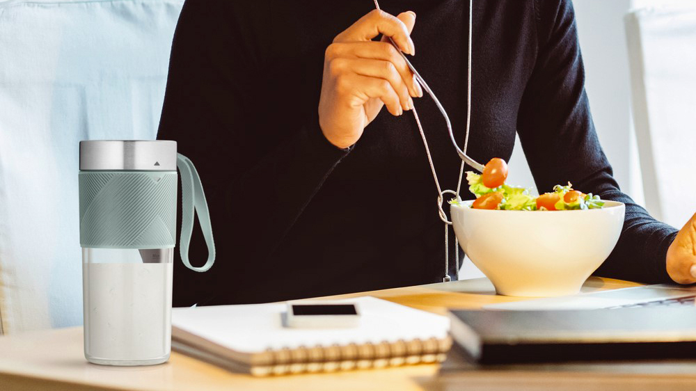 Žena, která jí u stolu, na kterém je položený smoothie mixér Tefal Smoothie Lightmix BL1C0430_03