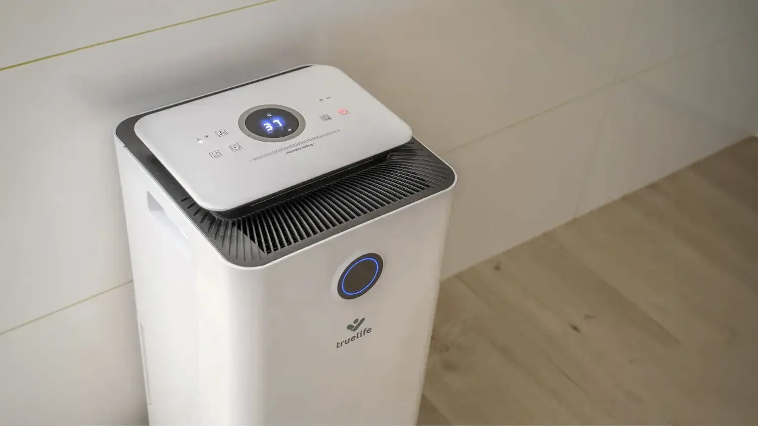 Odvlhčovač vzduchu TrueLife DH5 Touch stojící u zdi zobrazuje hodnotou vlhkosti na LED displeji
