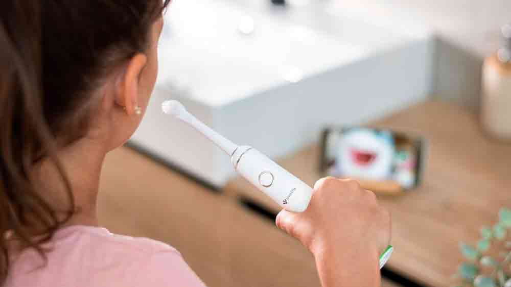 Dívka si čistí zuby a kouká na mobil se sonickým kartáčkem TrueLife SonicBrush Junior J100_03