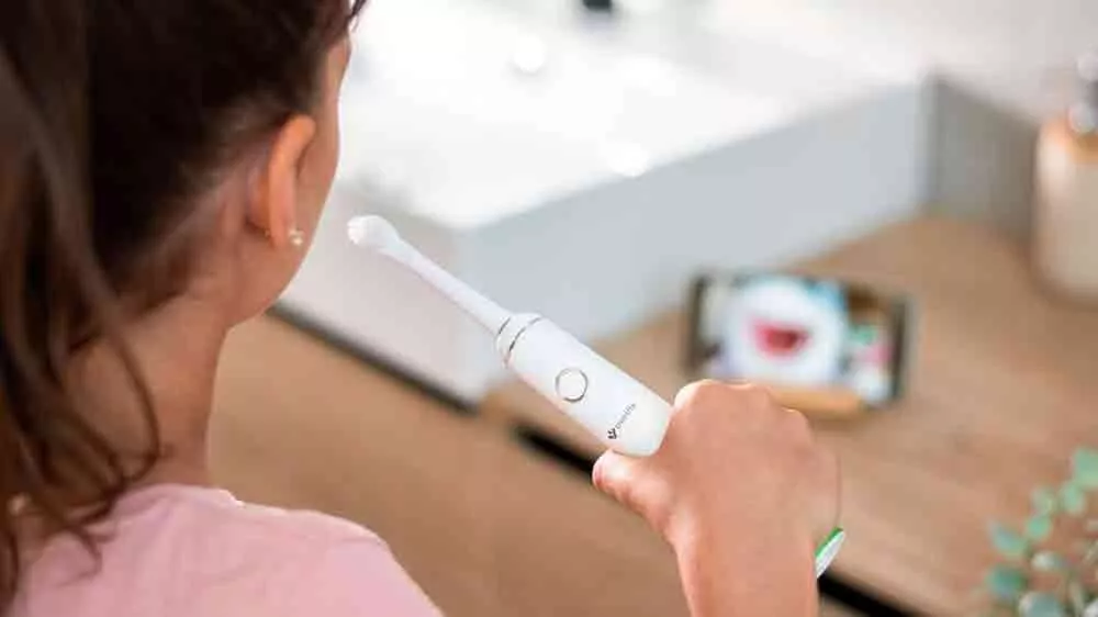 Dívka si čistí zuby a kouká na mobil se sonickým kartáčkem TrueLife SonicBrush Junior J100_03
