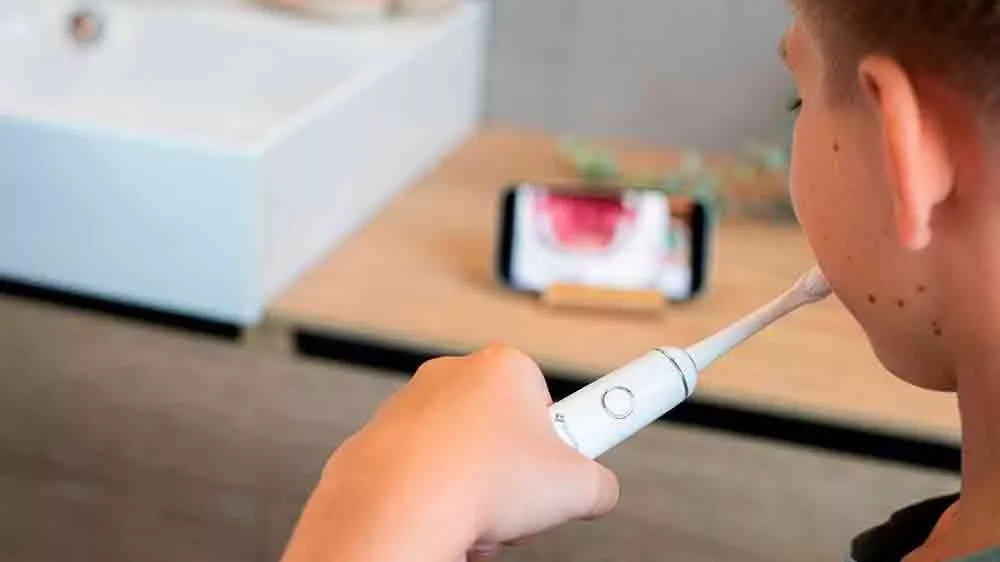 Chlapec si čistí zuby a kouká na mobil se sonickým kartáčkem TrueLife SonicBrush Junior J100_03