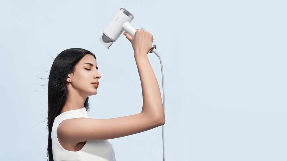 Žena si fénuje vlasy fénom Xiaomi High-speed Ionic s nadstavcom na styling_03