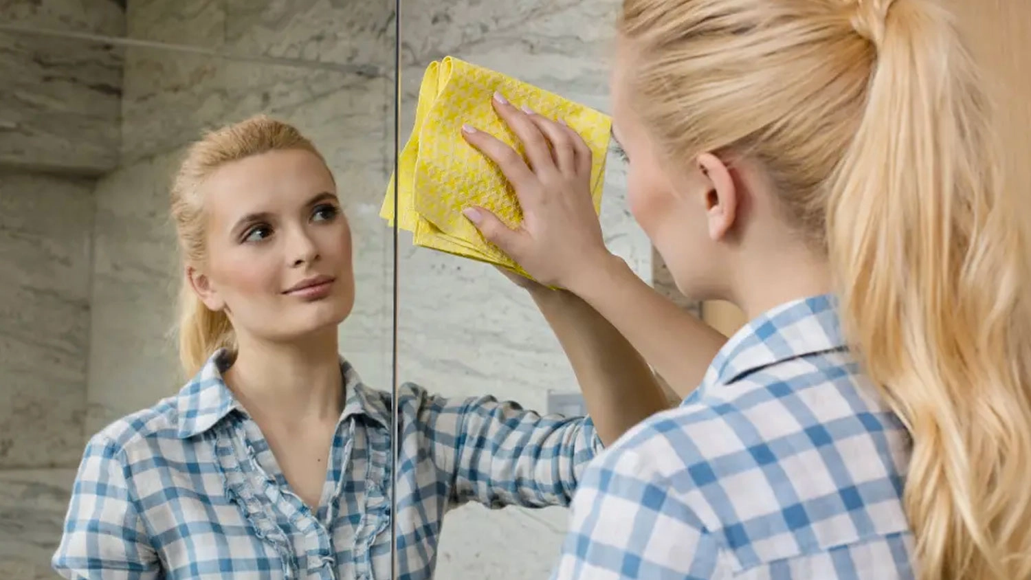 Žena le&scaron;t&iacute; zrkadlo handričkou na okn&aacute; Vileda Actifibre