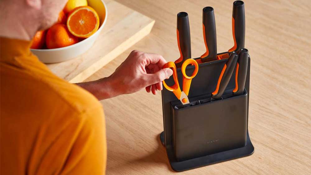 Muž vytahuje nůžky z plastové bloku s pěti noži Fiskars Functional Form 1057554 krájení surovin_02
