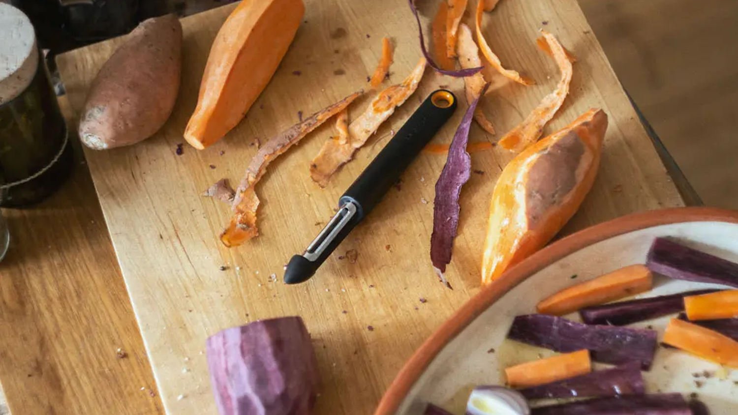 Škrabka Fiskars – otočná (1079960) na prkénku se zeleninou