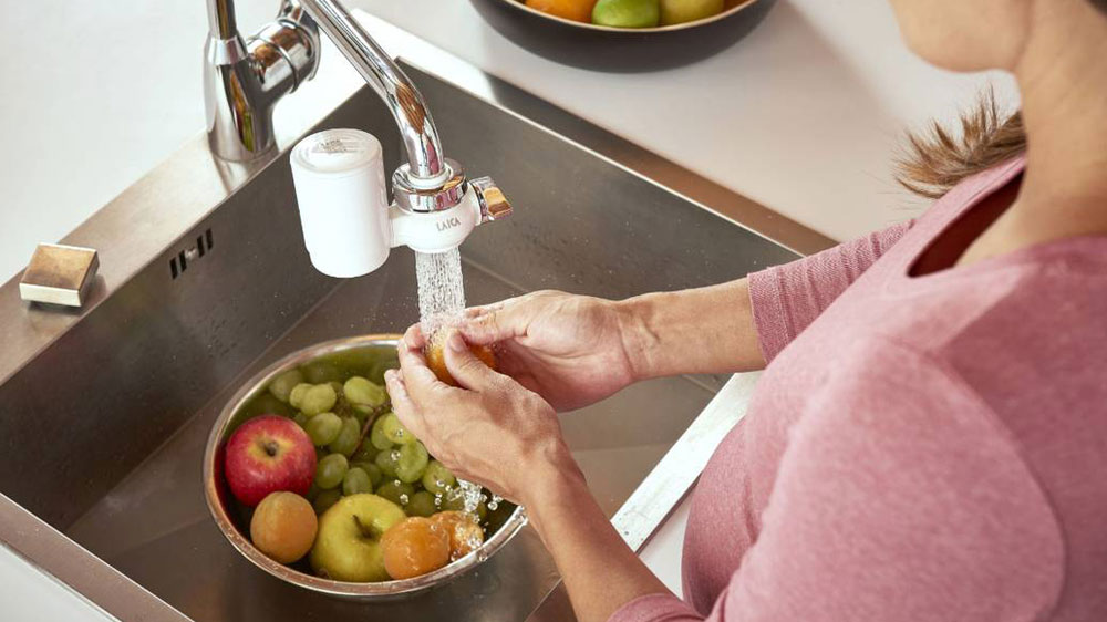 Žensk&eacute; ruce um&yacute;vaj&iacute;c&iacute; ovoce v m&iacute;se ve dřezu pod tekouc&iacute; vodou s instalovan&yacute;m filtračn&iacute;m syst&eacute;mem Genova R20A+Hydrosmart filtrem Laica_02
