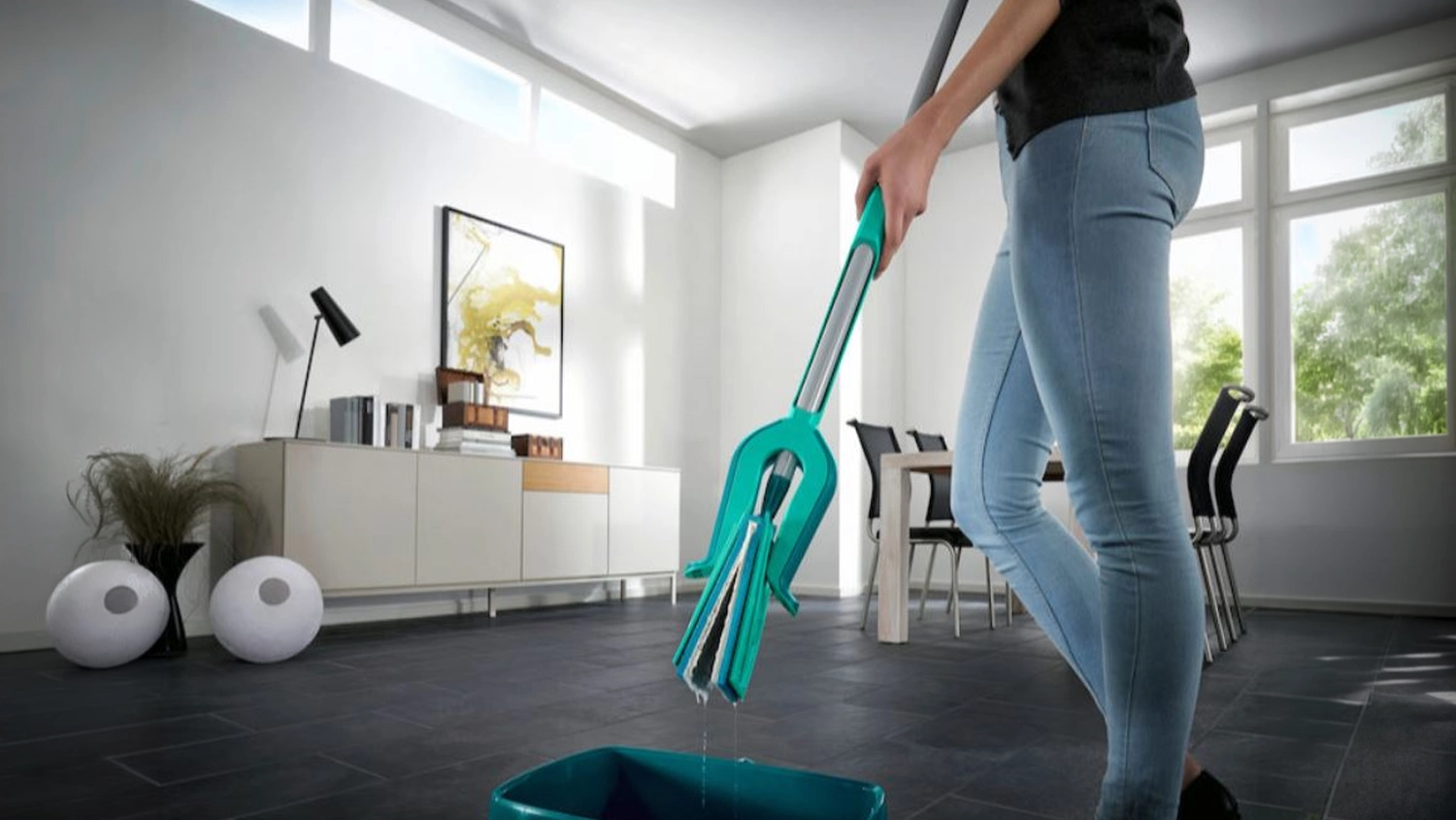 Žena namáčí do kbelíku podlahový mop Leifheit