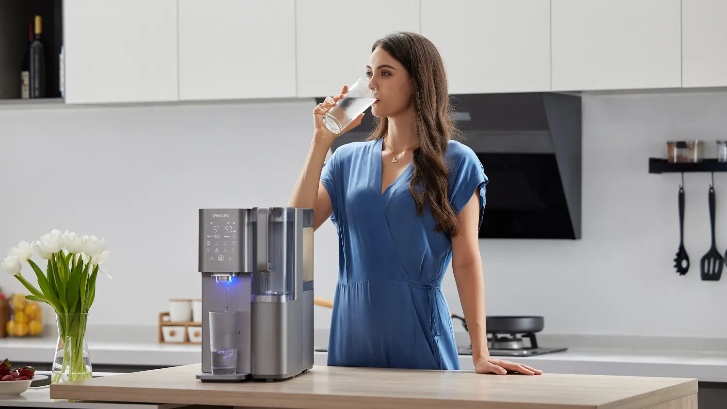 Žena vychutnávající si vodu z výdejníku vody Philips ADD6921DG/10