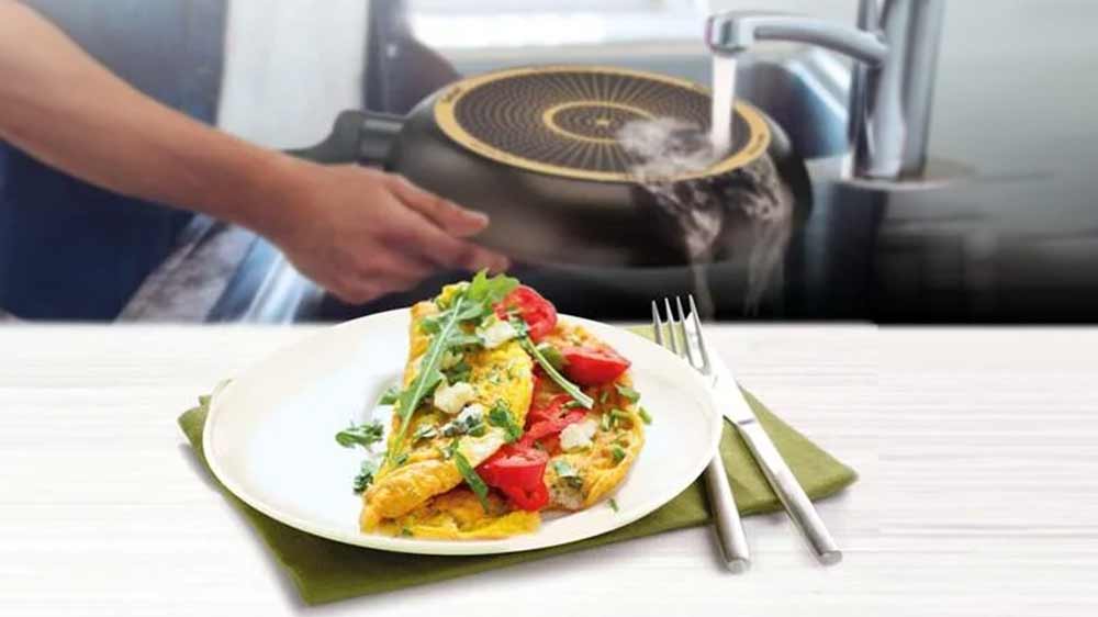 V popředí vaječná omeleta na talíři, v pozadí muž myje pánev Tefal Simple Cook_02